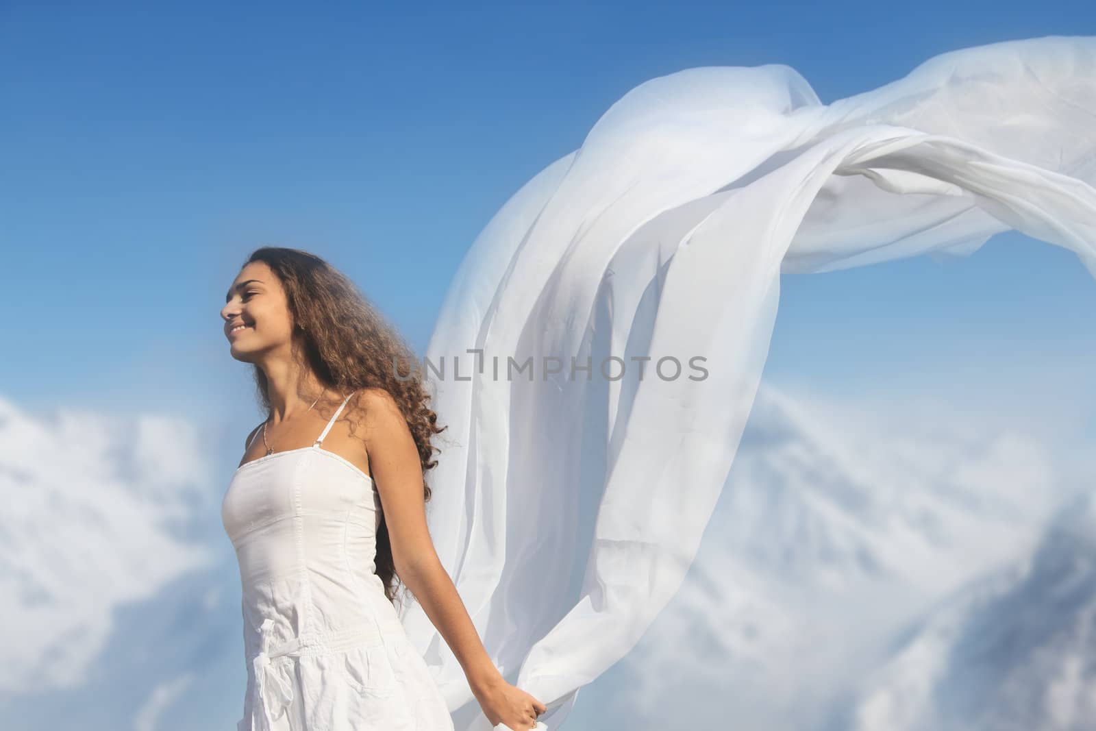 Young fresh woman with flying fabric on top of the mountains