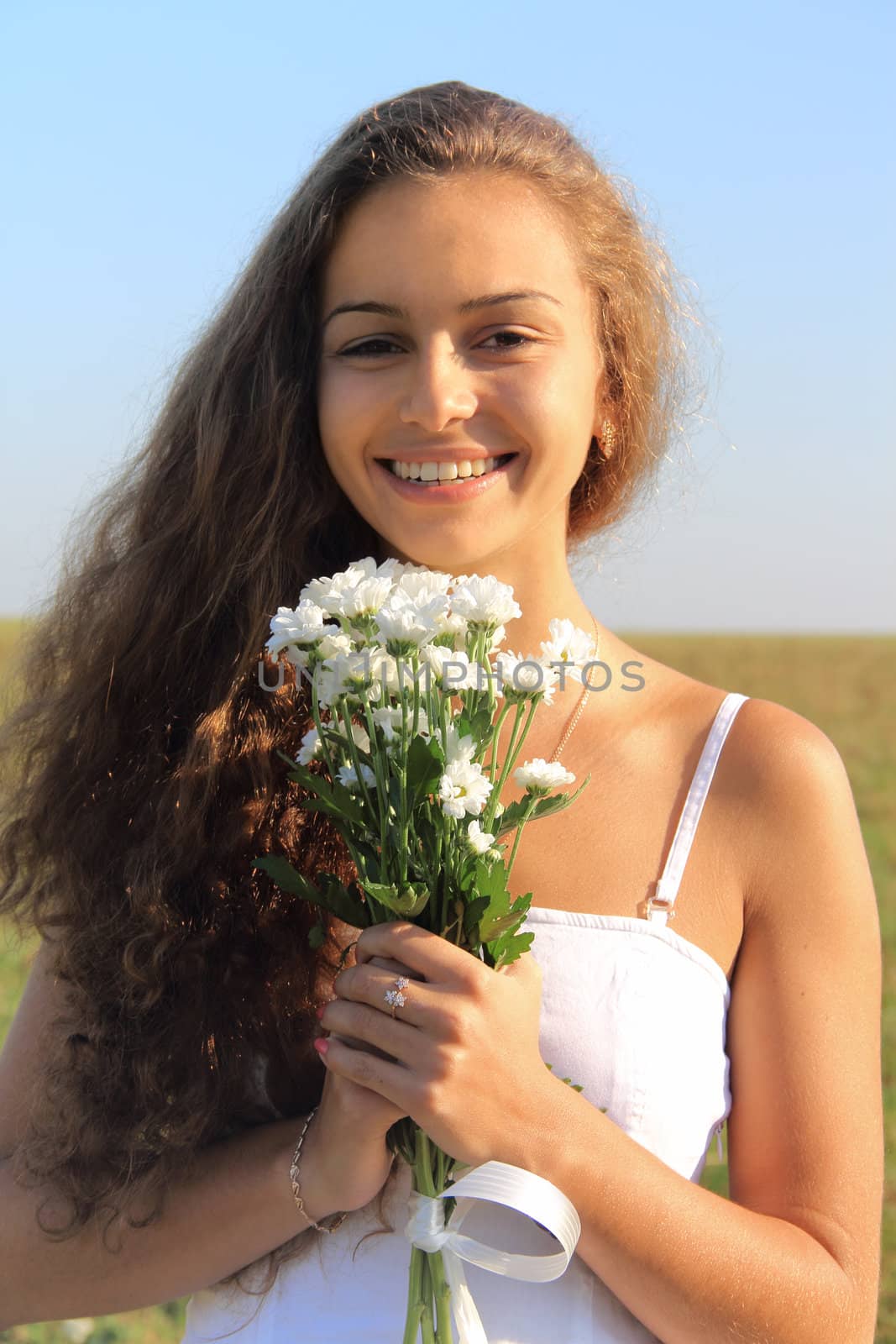 Smiling young woman with white flowers at sunny day