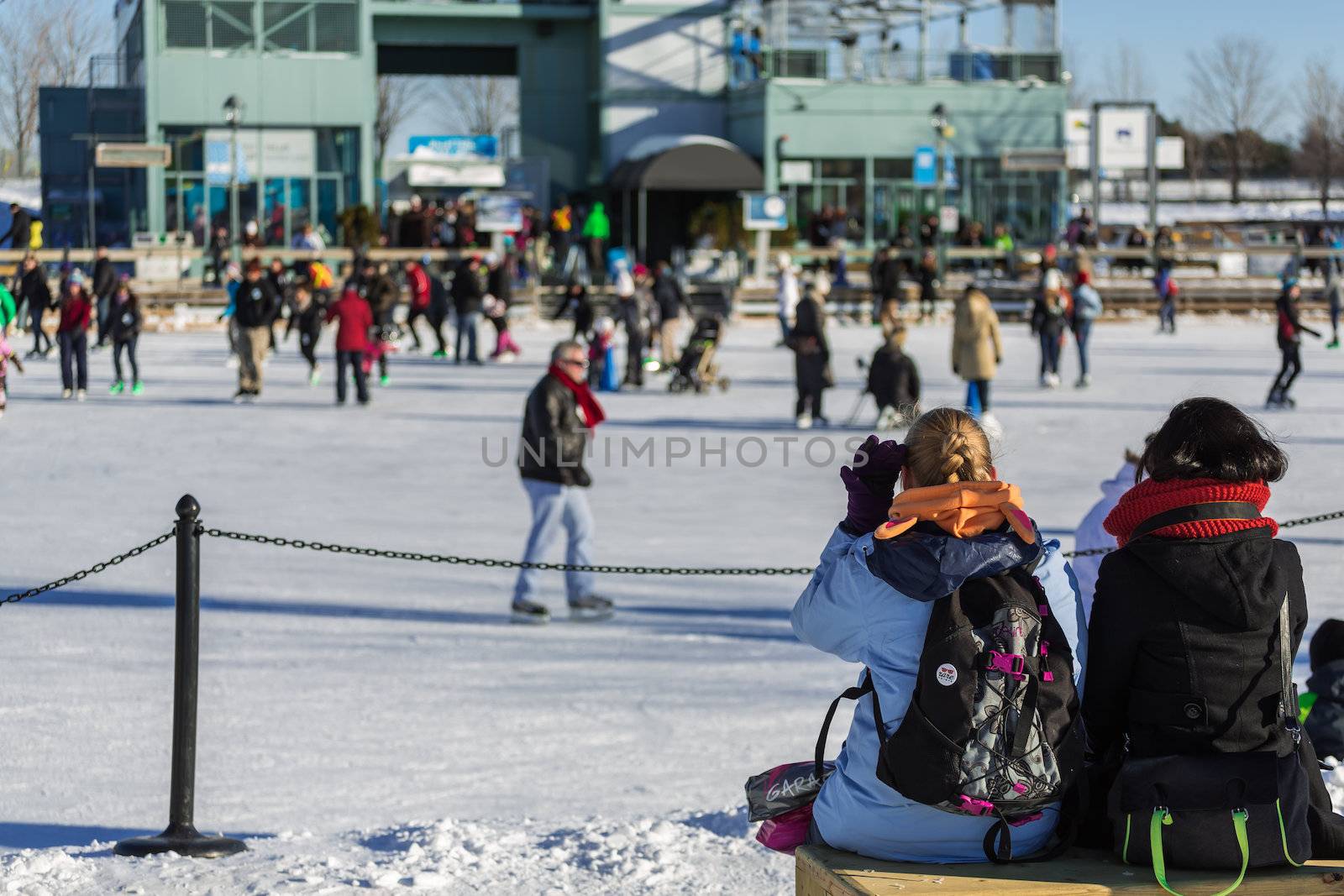 Two girls are sitting and talking with each other while looking on the Skating Rink in Old Port of Montreal, Quebec ,Canada