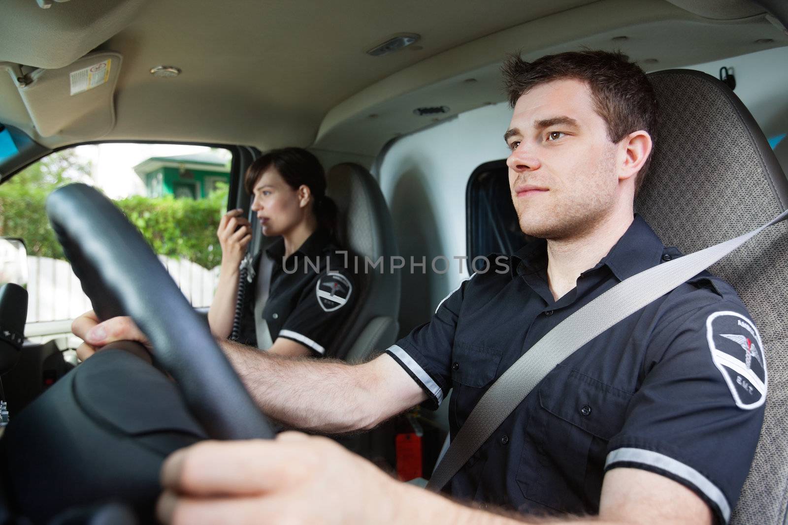 Portrait of EMS worker driving ambulance while team member talks with dispatcher