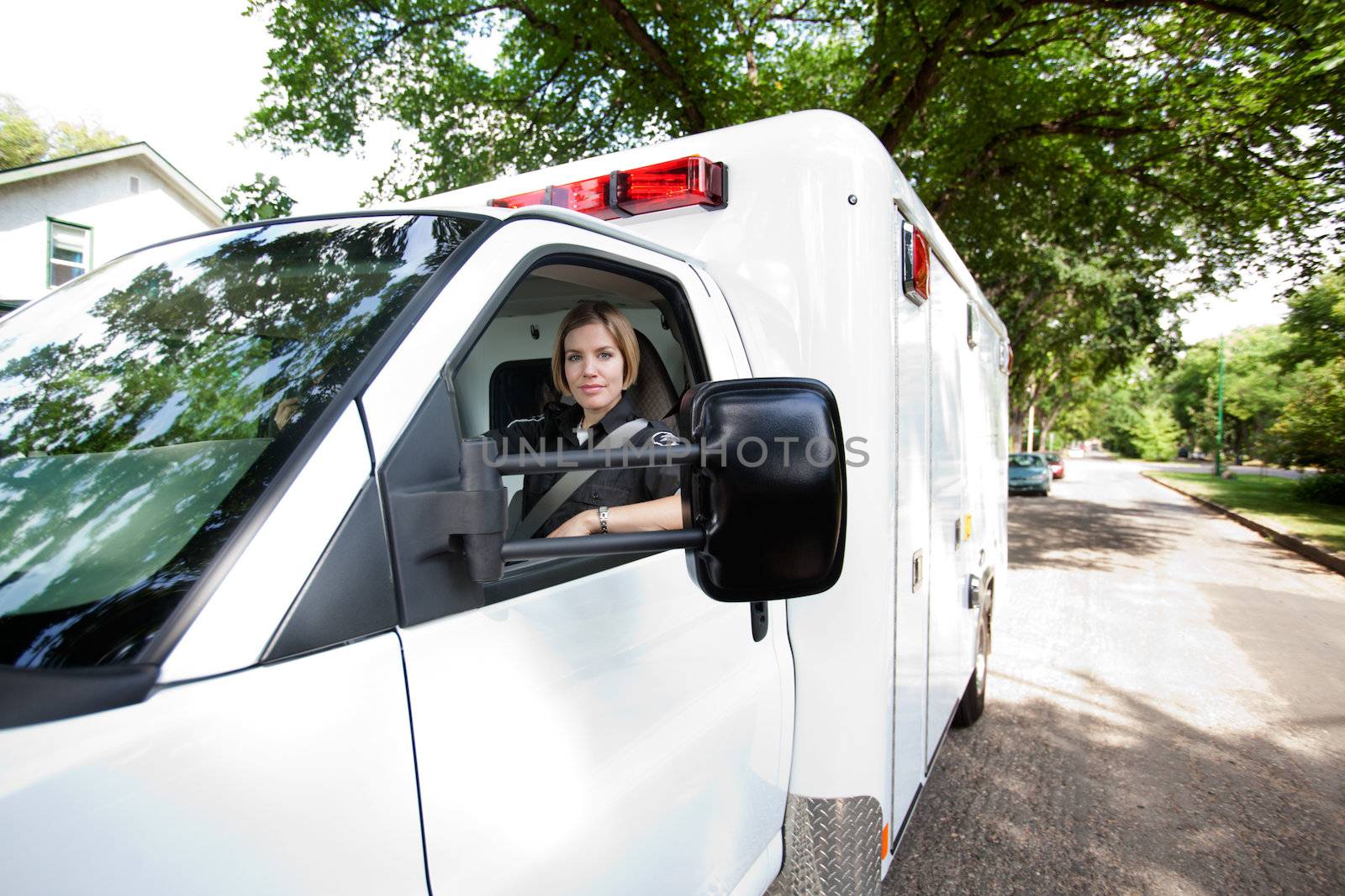 Portrait of a paramedic woman driving an ambulance in a residential city area