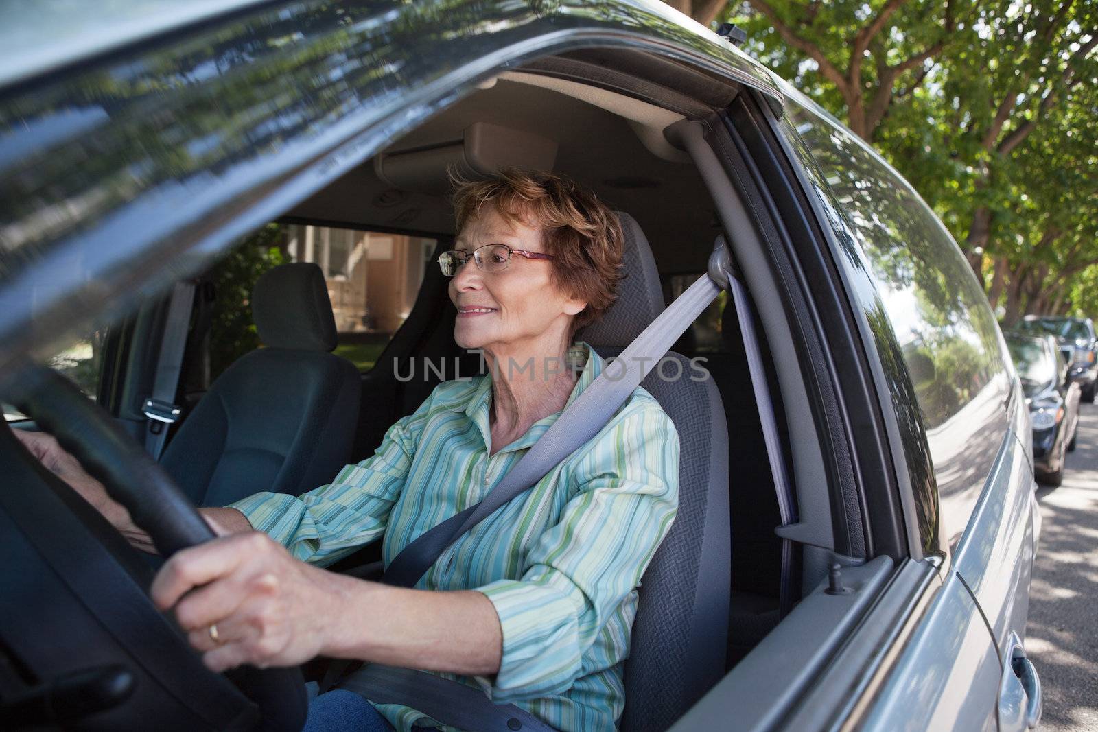 Active senior woman smiling while driving car