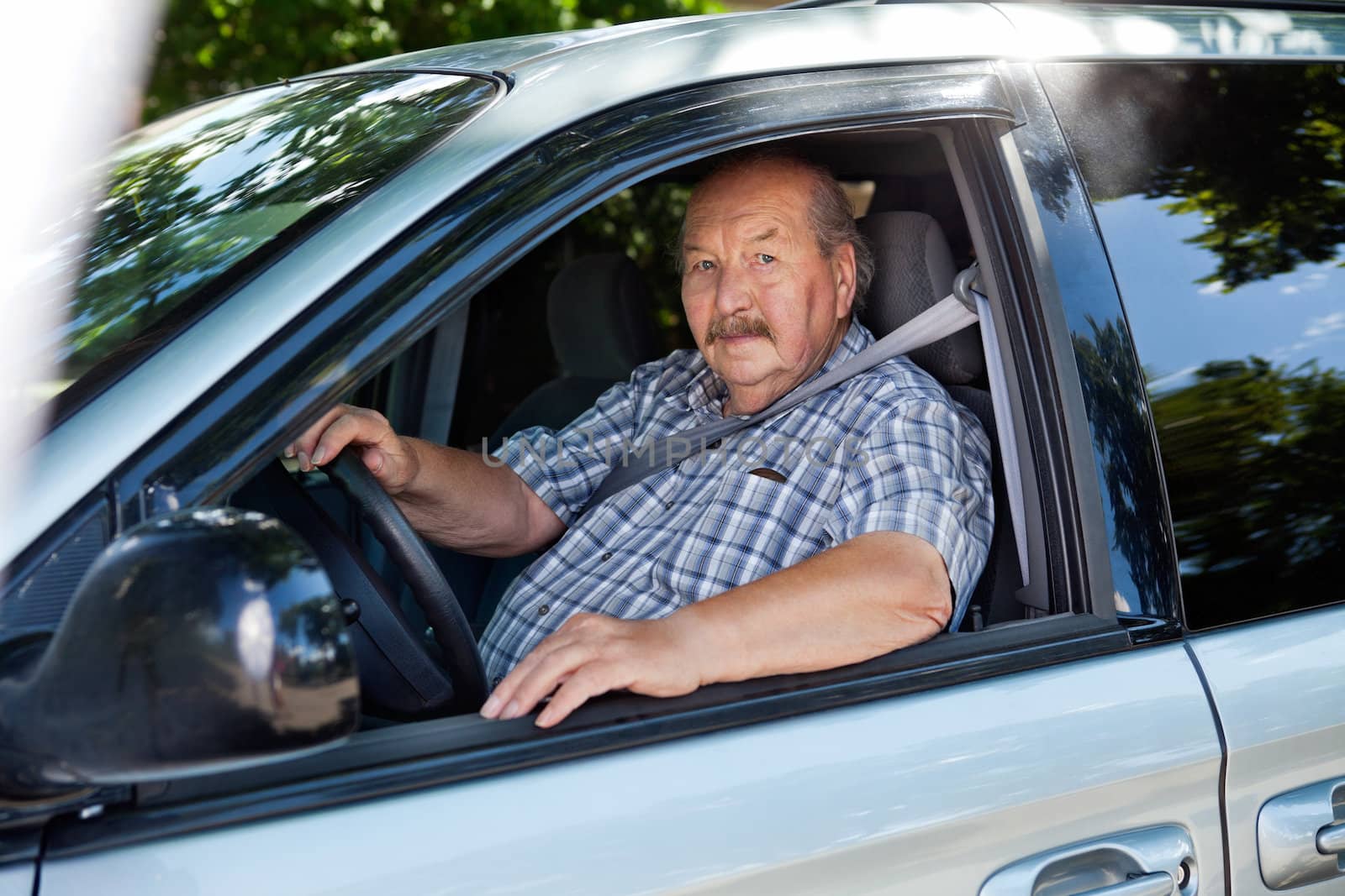 Portrait of an elderly man driving a car