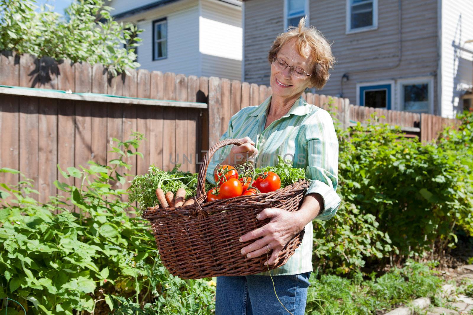Smiling senior woman holding basket filled with vegetables