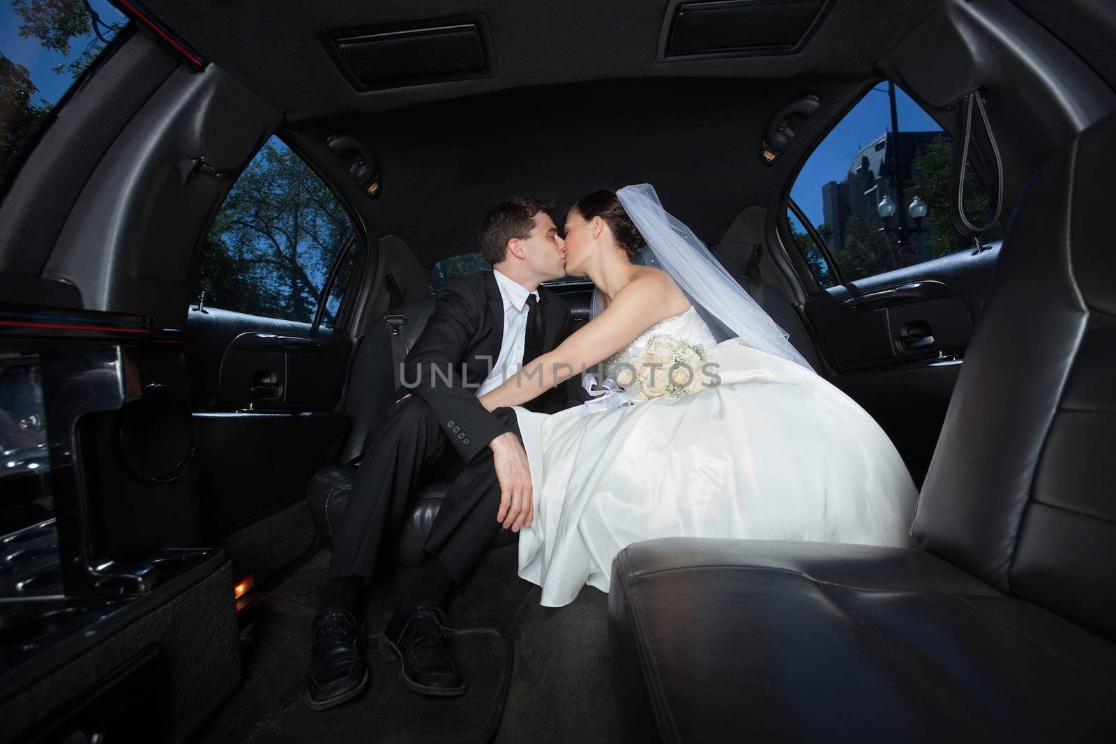 Newlywed couple kissing each other in limousine