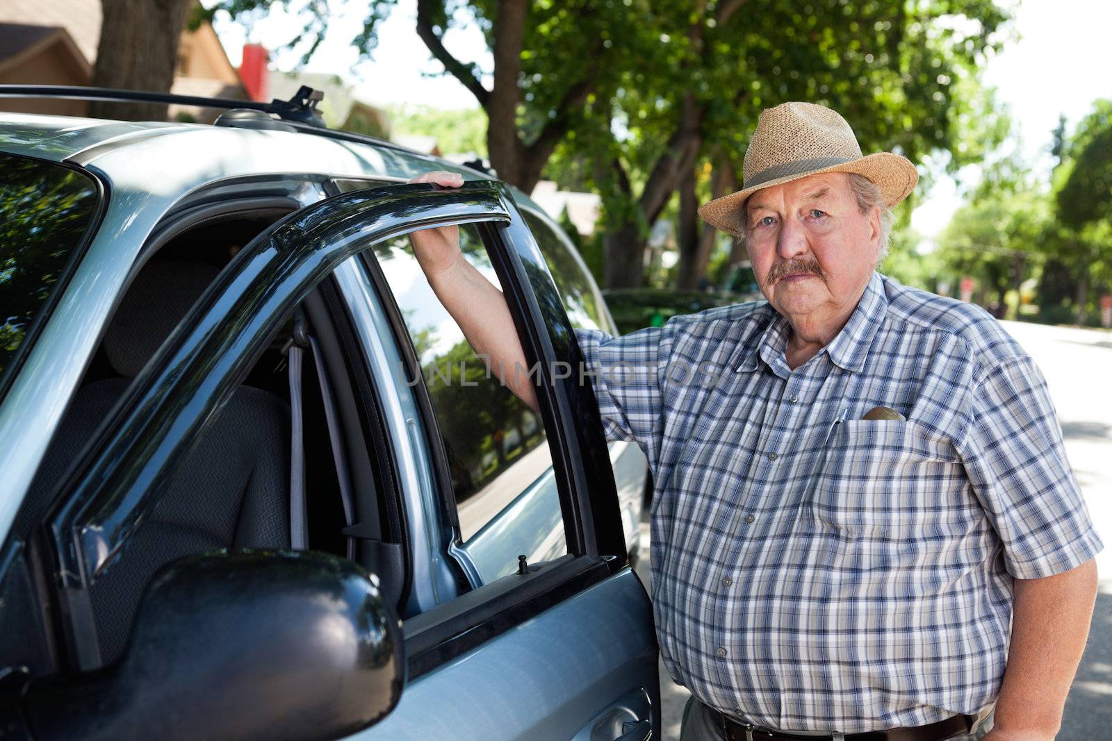 Portrait of senior man standing near car