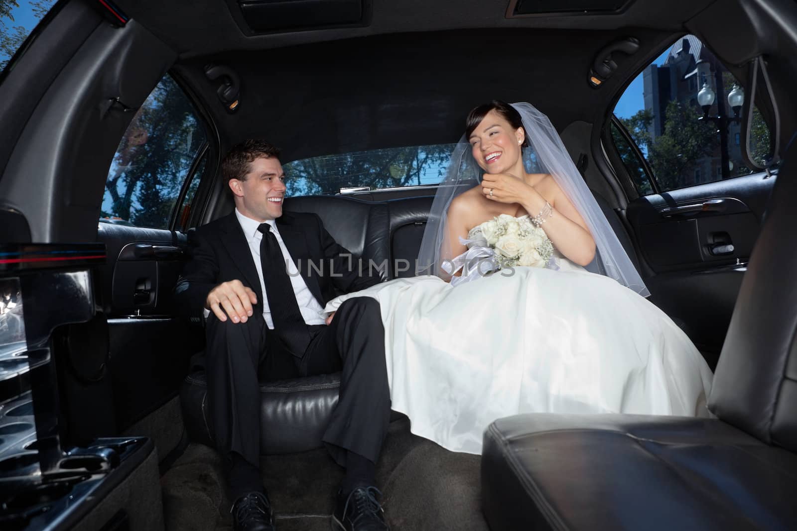 Newly wed couple in limousine by leaf