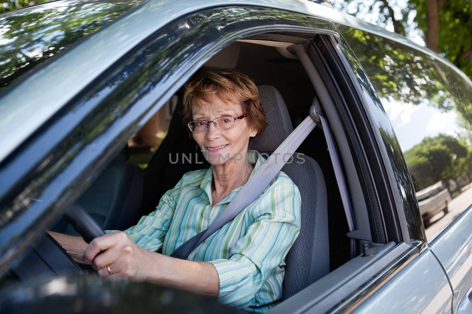 Senior woman driving car by leaf