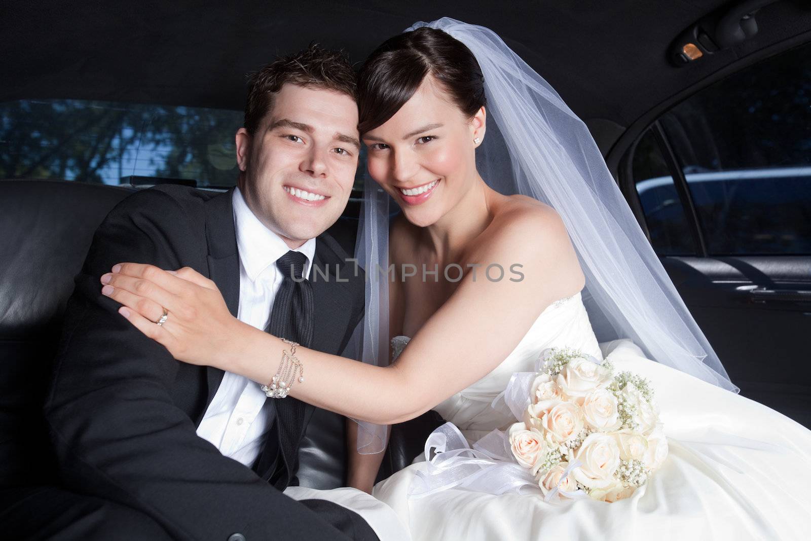 Portrait Of Newlywed Couple Smiling Sitting In Limousine.
