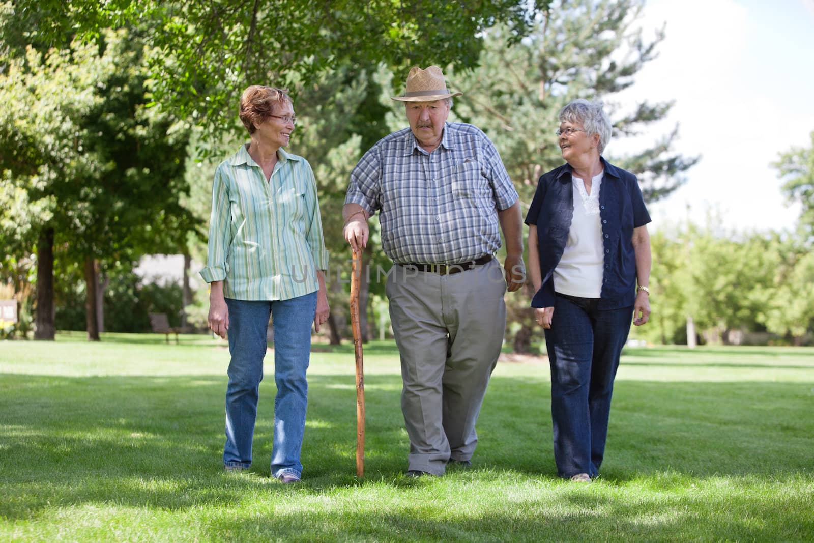 Senior Friends Walking in Park by leaf