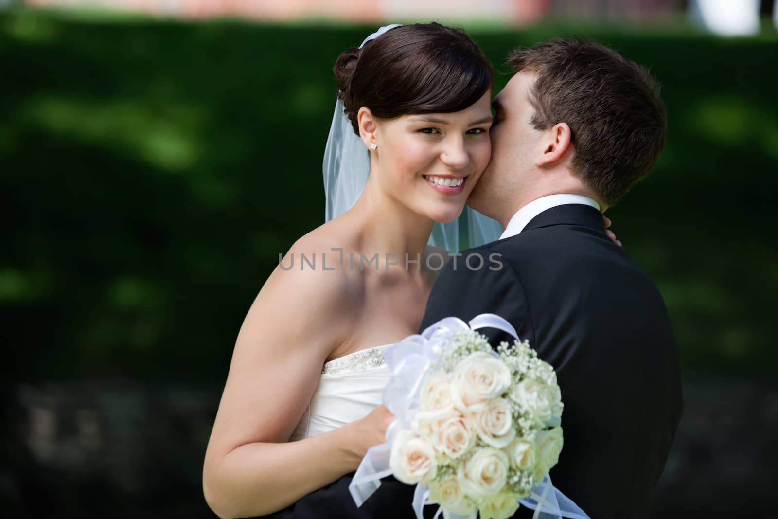 Groom sneaks a kiss on bride's cheek