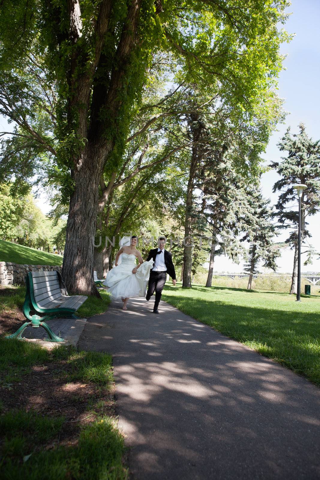 Newlywed happy bride and groom running along the walkway