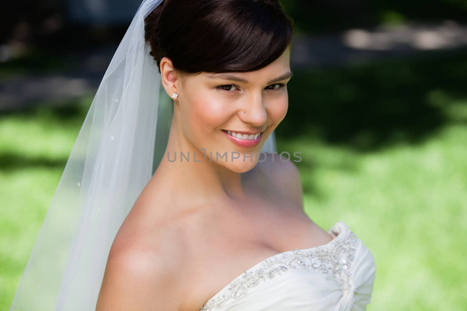 Pretty young bride smiling by leaf