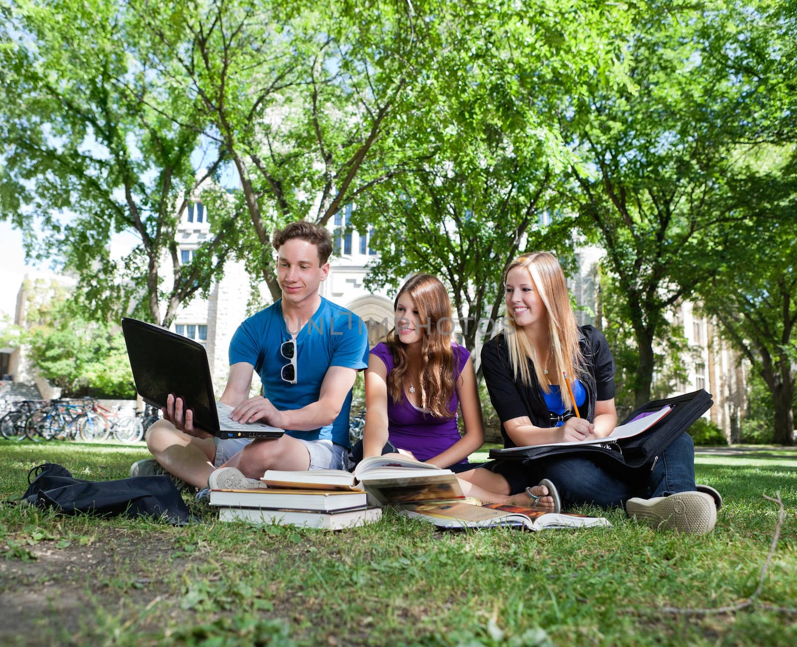 Teenagers studying on campus lawn by leaf