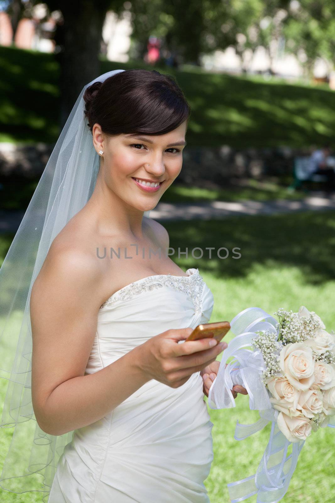Portrait of smiling newlywed bride holding cell phone