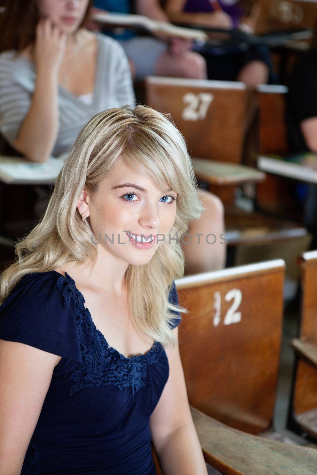 Portrait of college girl sitting in auditorium by leaf