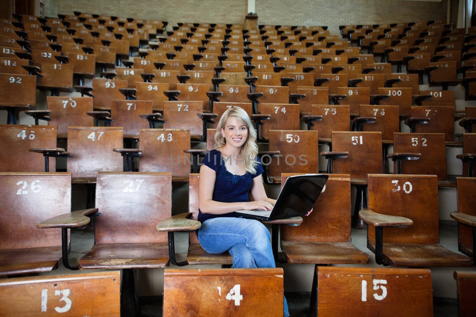 Portrait of young college student using laptop at university hall