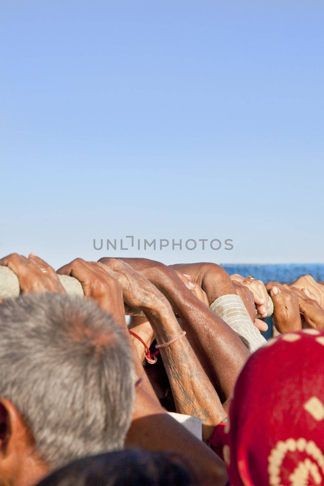 Vertical capture of passengers holding on the safety rail in a crowed ferry between Bet Dwarka and the India mainland. Clear blue cloudless sky in Gujarat India