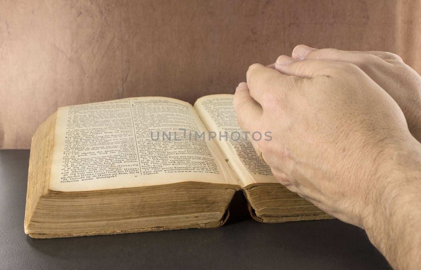 praying hand with old bible book with brown background