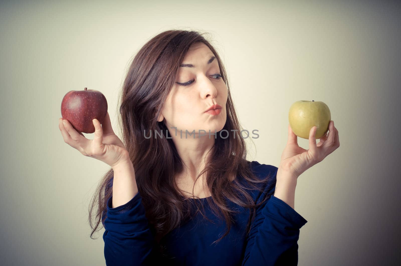 beautiful woman choosing red or yellow apples on gray background