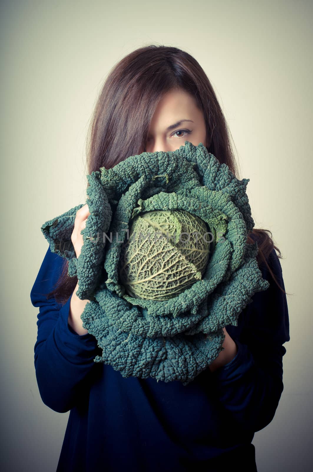 beautiful woman with savoy cabbage on gray background