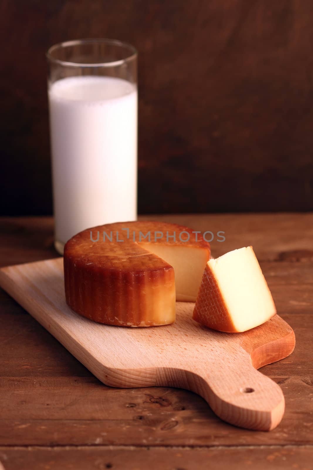 Yellow cheese on wooden board and a glass of milk