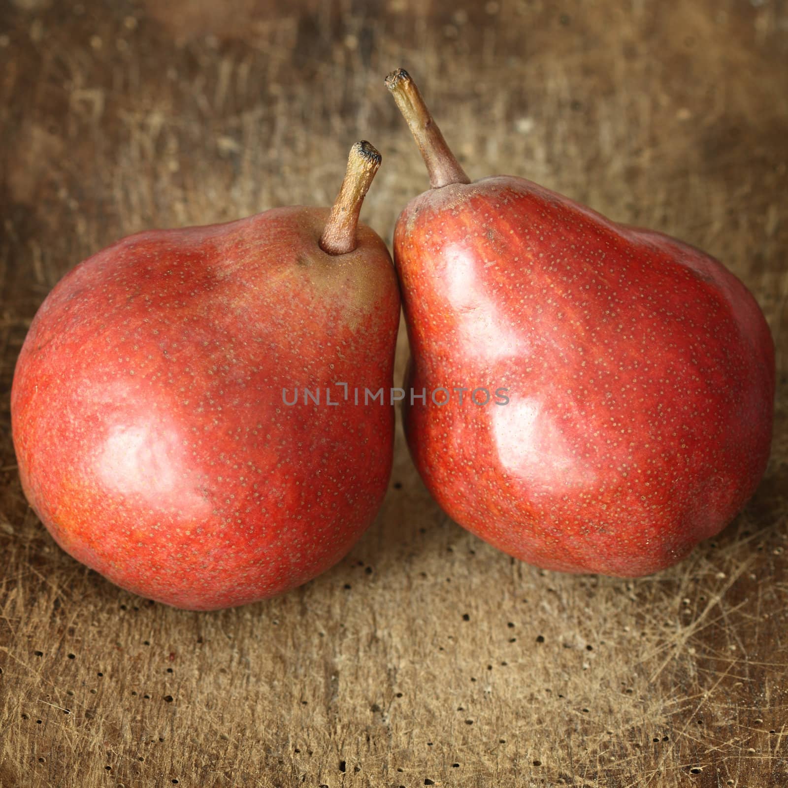 two red pears on wooden table close up