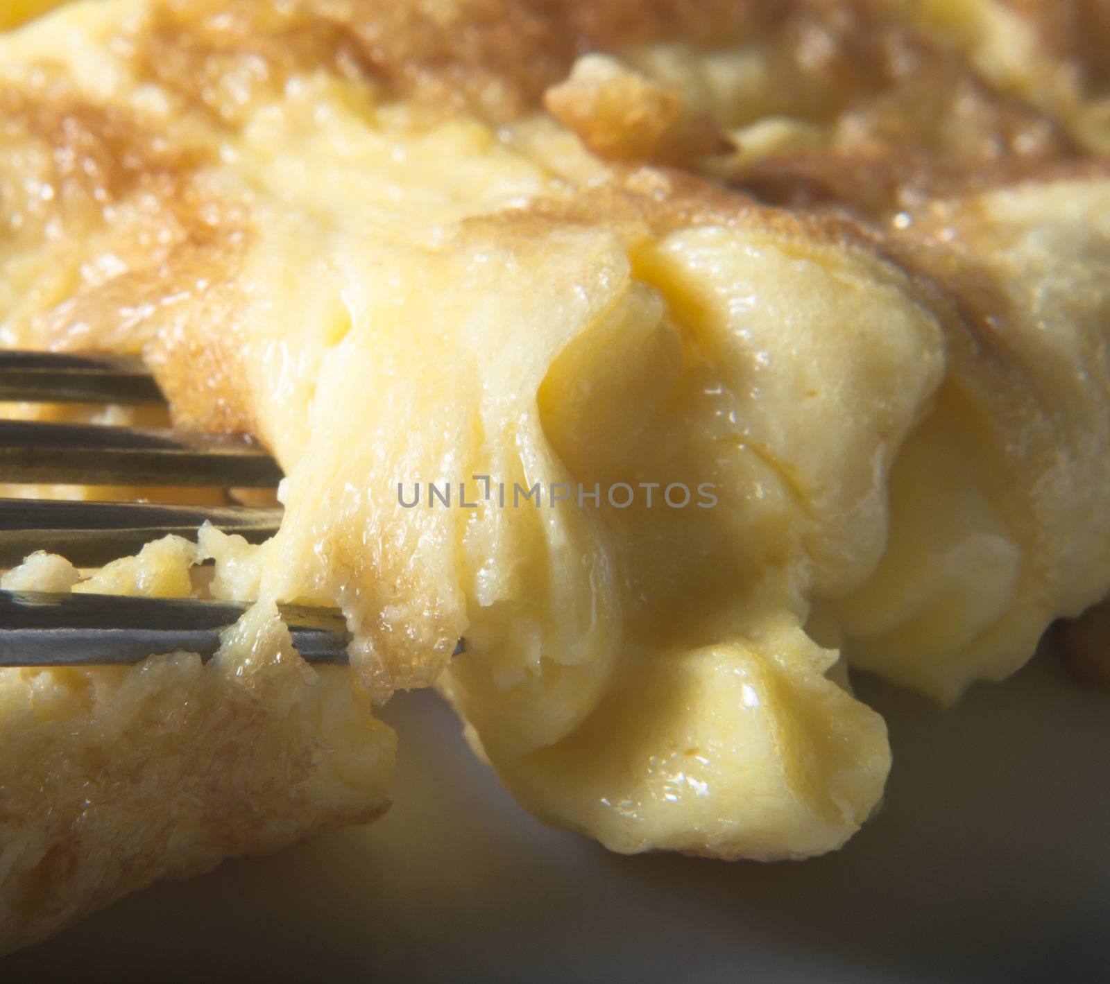 Close up (macro) shot of a fork piercing a served omelette.  Selective focus.