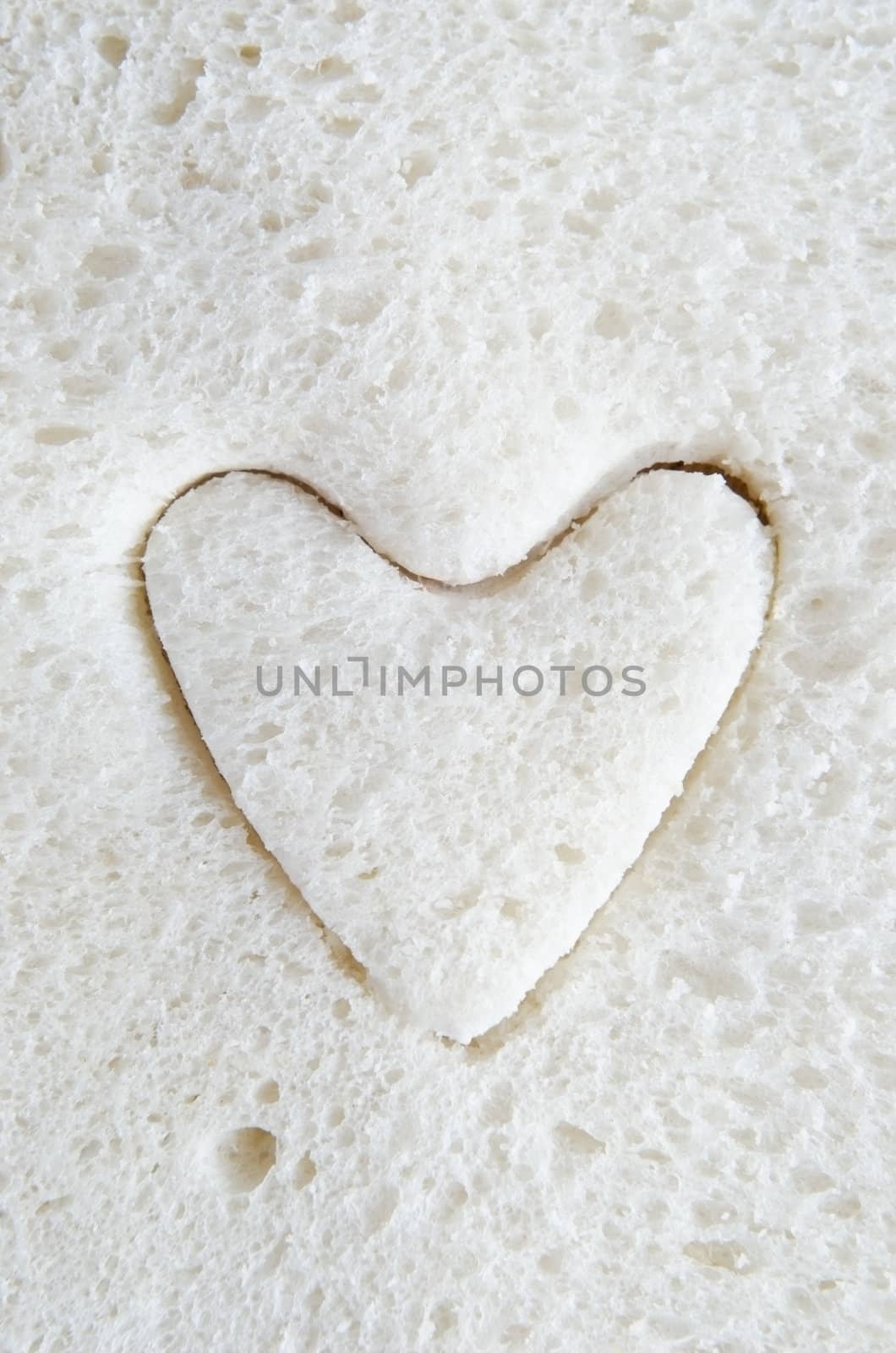 Close up (macro) of white bread with a heart shape cut into it.