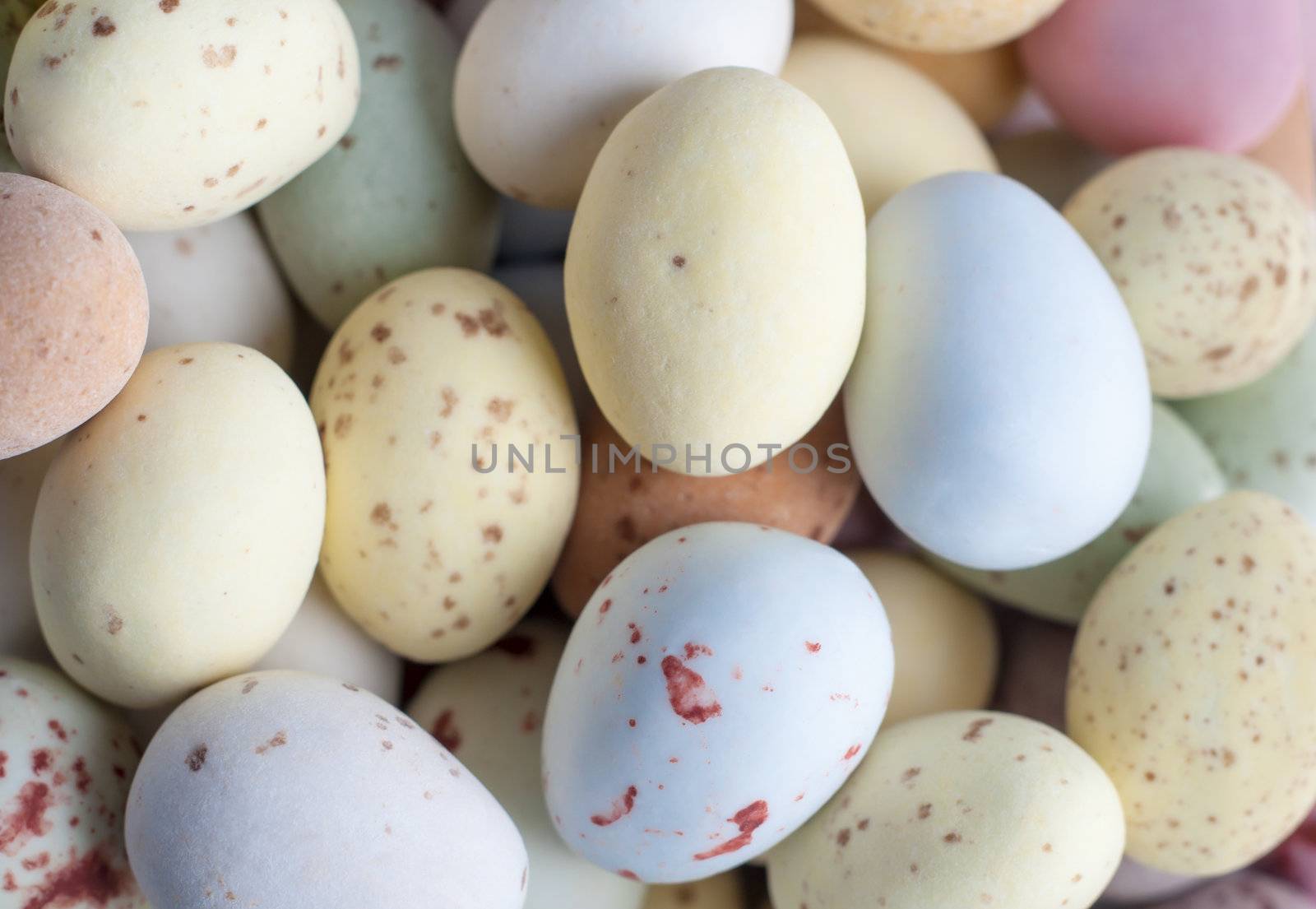 Overhead close up (macro) of a pile of Egg shaped Easter sweets (candies) in pastel shades.