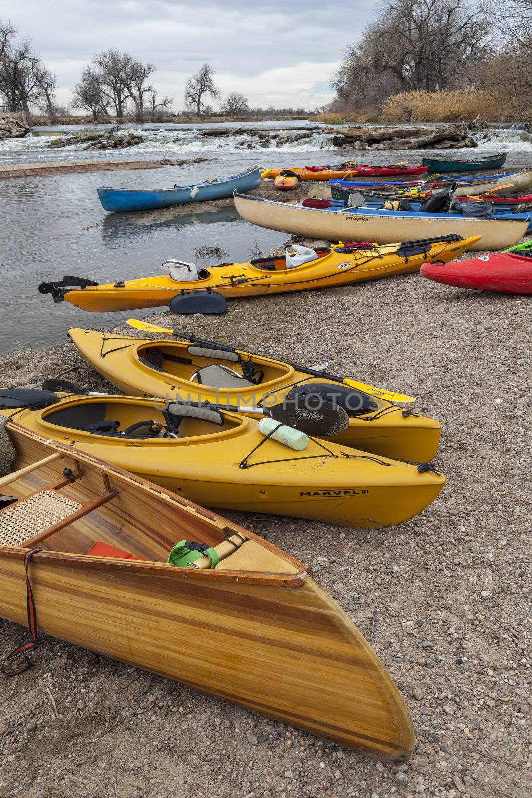 SOUTH PLATTE RIVER, EVANS, COLORADO - APRIL 6: Kayaks and canoes on a river shore below diversion dam during Annual All Club Paddle on April 6, 2013, a popular season opening paddling trip in northern Colorado.