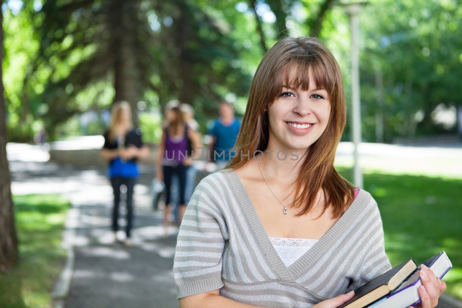 Portrait of smiling young college girl by leaf