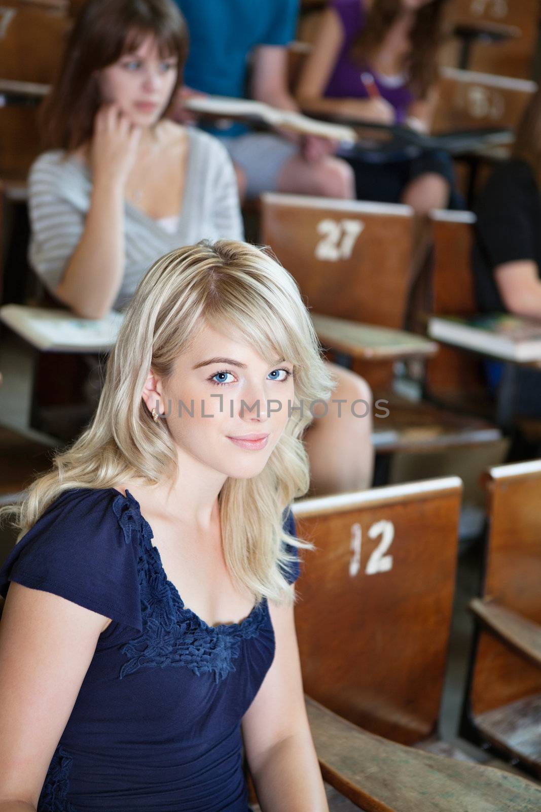 Portrait of college girl sitting in auditorium by leaf