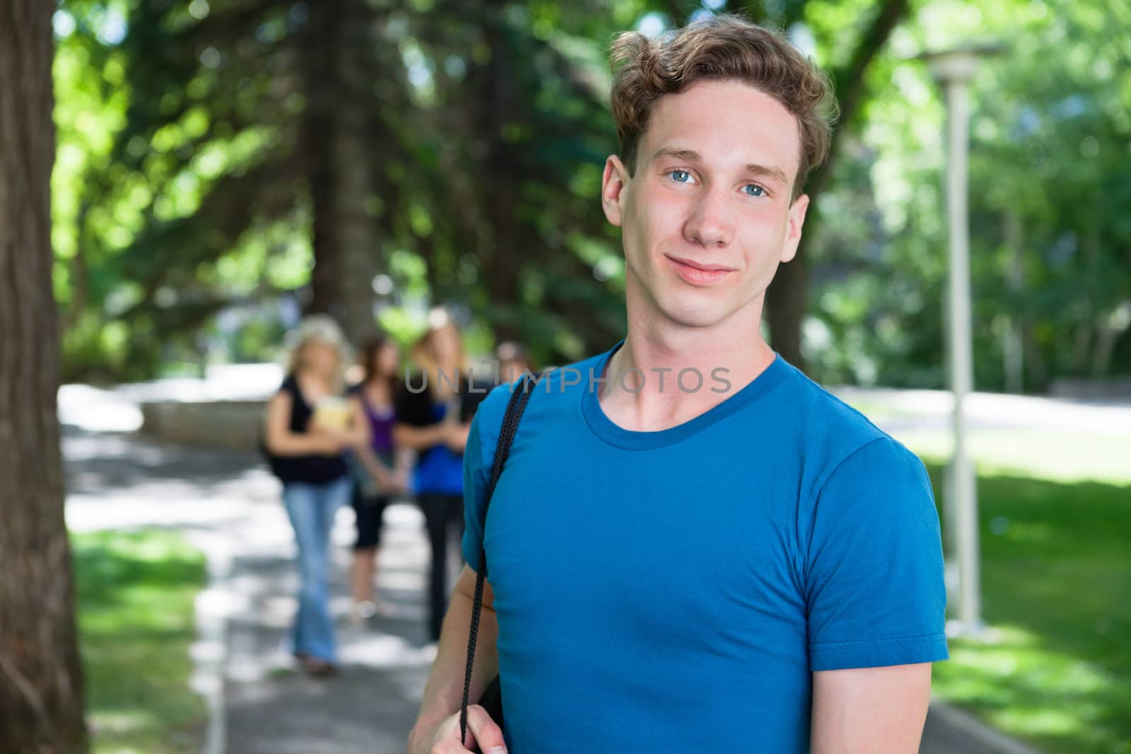 Portrait of young male smiling while his classmates walking in the background