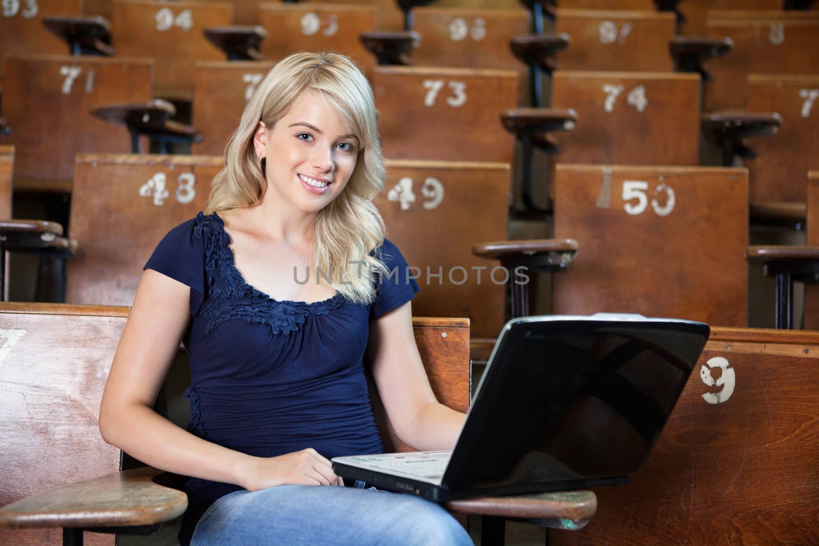 Portrait of sweet young college girl using laptop in university lecture hall