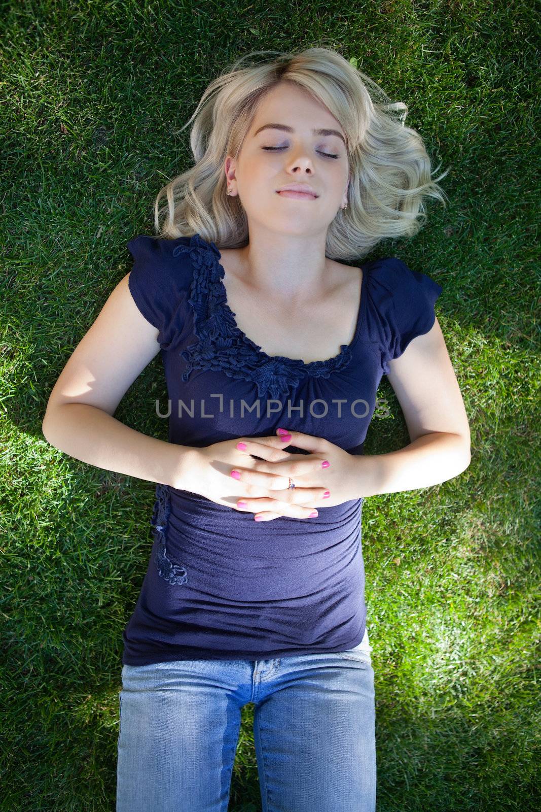 Young woman lying on grass by leaf