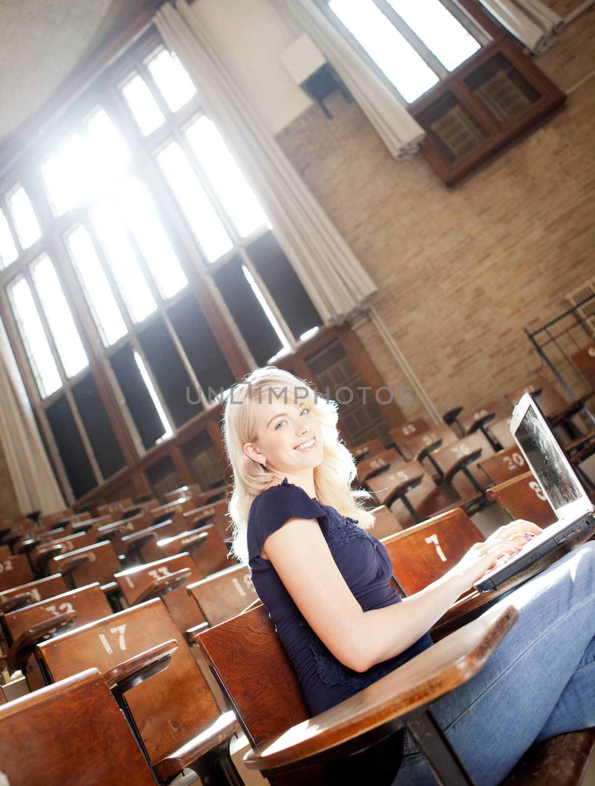 Portrait of a young college girl in a lecture hall with laptop