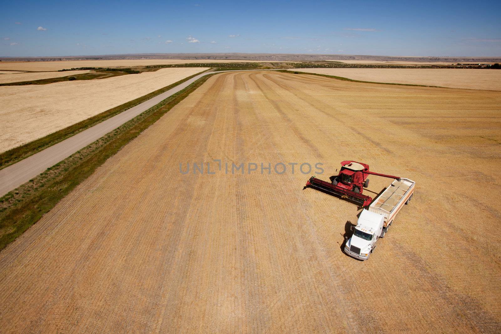 Aerial shot of a combine emptier a hopper into a semi truck on the prairie
