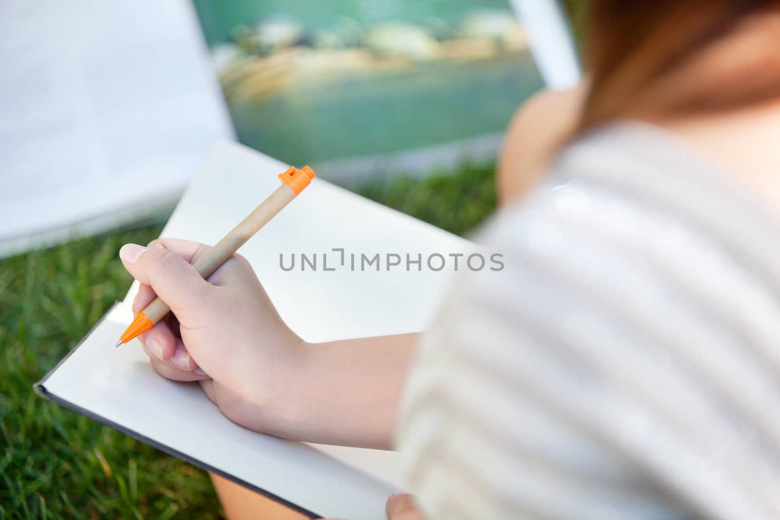 Girl writing in a notebook by leaf