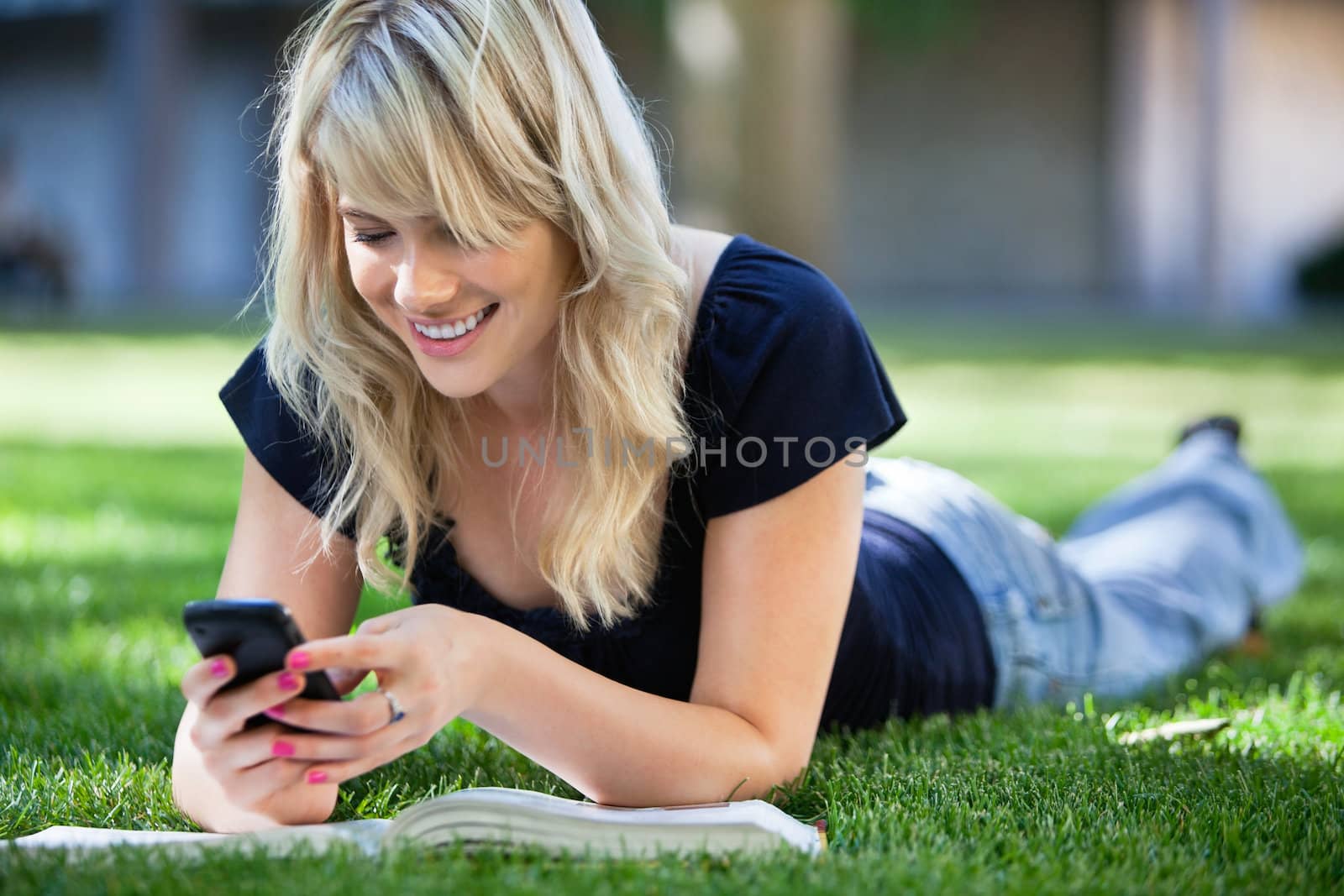Happy young girl using cell phone by leaf