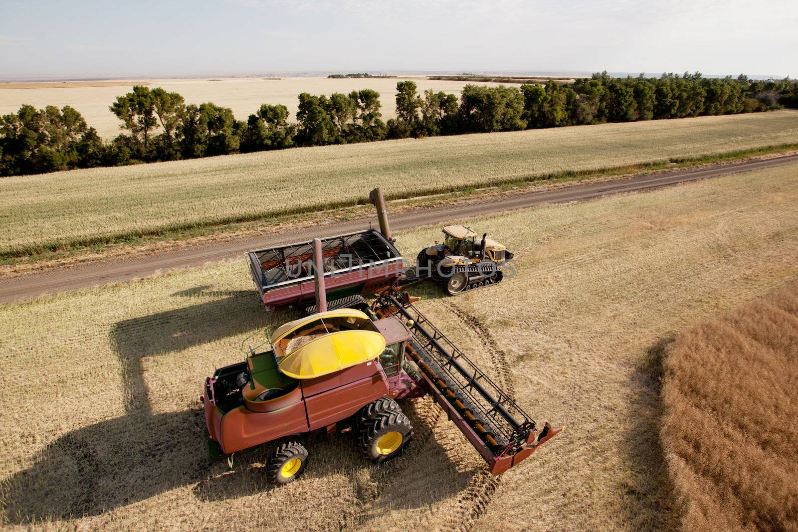 Large combine unloading seed into a grain cart on a prairie field