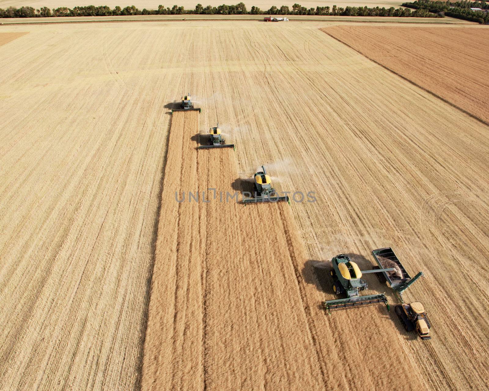 Four harvesters combing on a prairie landscape in formation