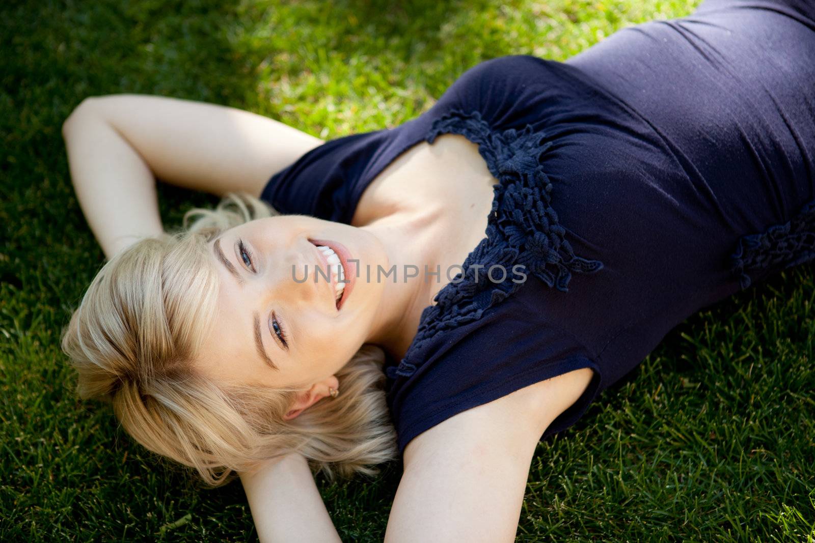 Young student woman laying on grass looking to sky dreaming
