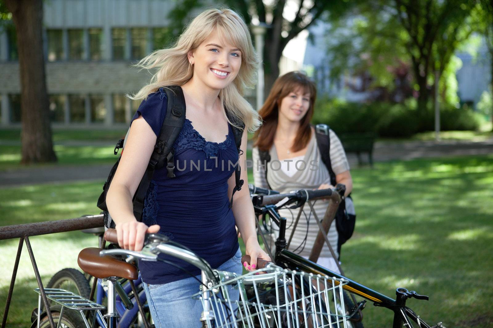 College students standing with bicycle on college campus lawn