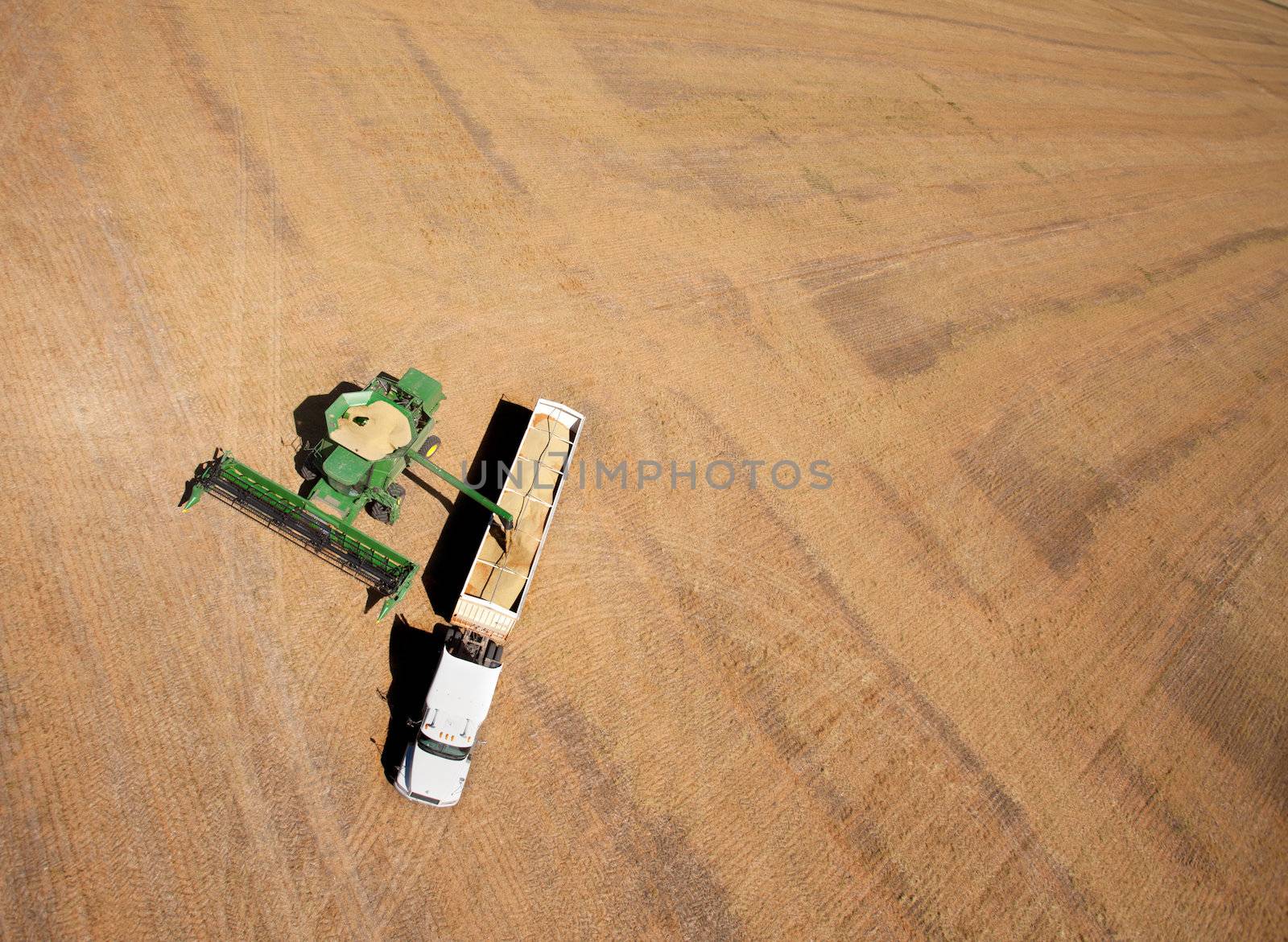 Aerial view of a field being harvested - a combine and truck in the foreground
