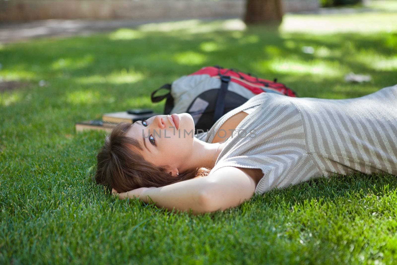 Girl lying down at college campus by leaf