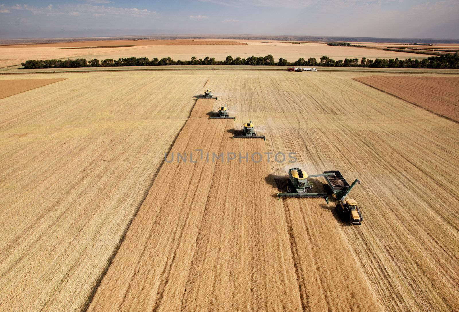 Four harvesters combing on a prairie landscape in formation