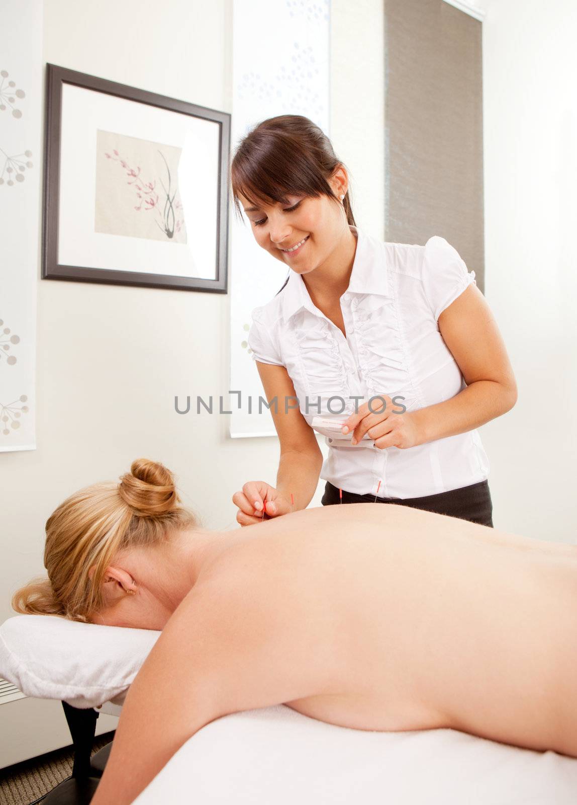 A woman acupuncturist performing a back treatment on a female pasient.