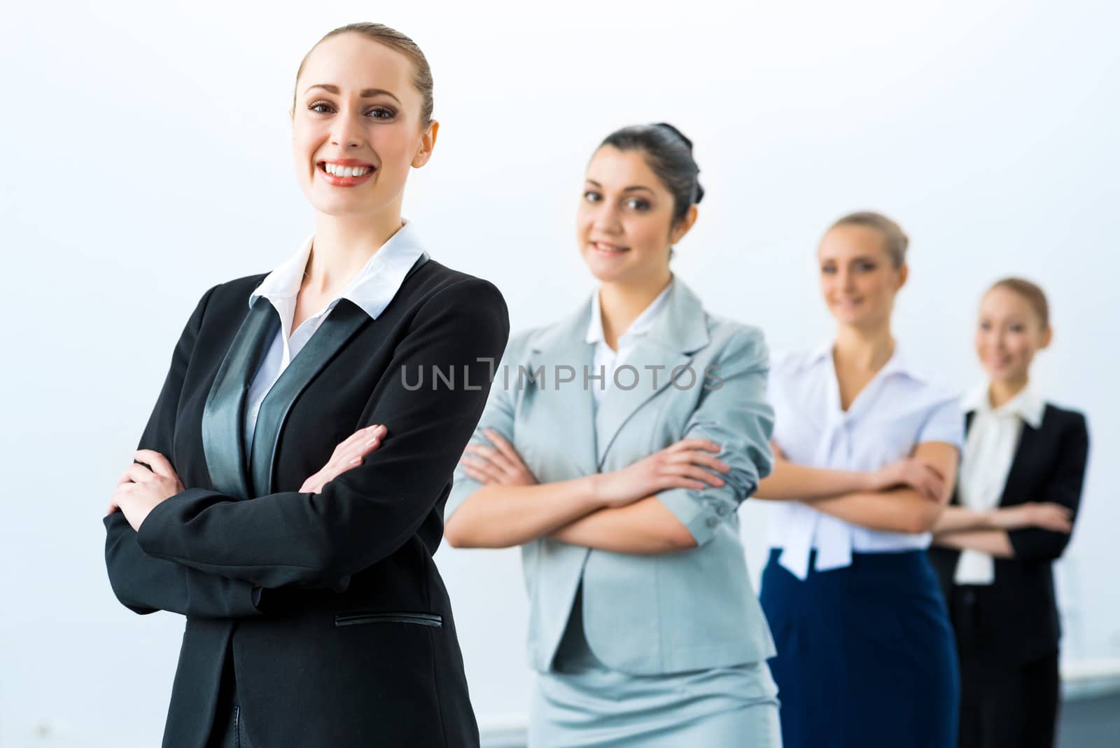 group of business people standing in a row, smiling and crossing his arms