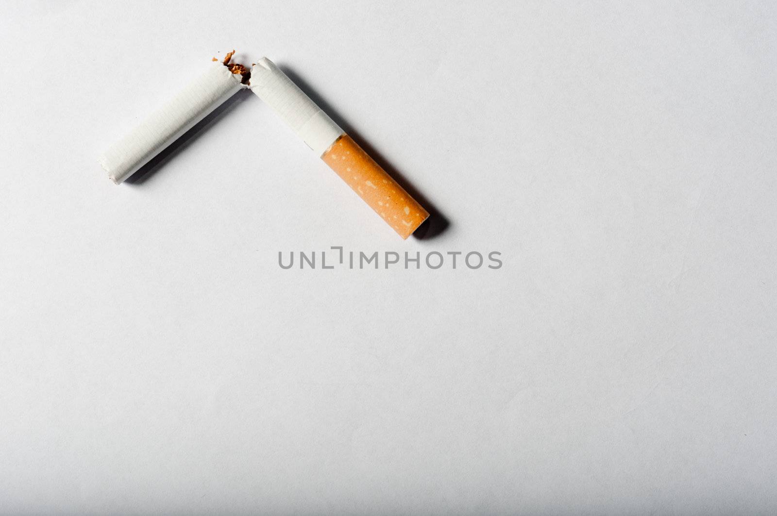 Broken cigarette on white background with harsh shadows by svedoliver